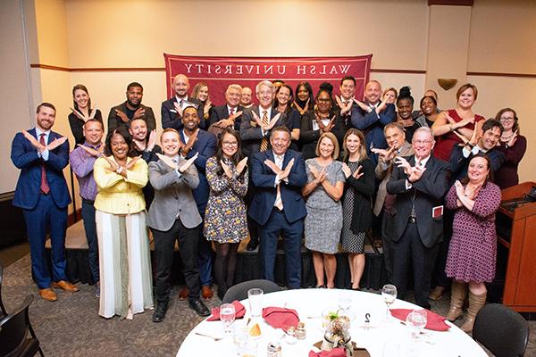 Group shot of alums with Swords Up hand gesture