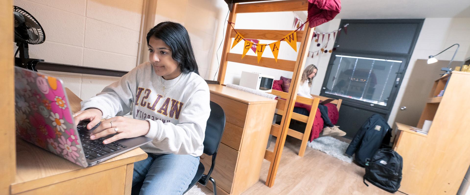 两名女学生在宿舍用笔记本电脑工作的照片